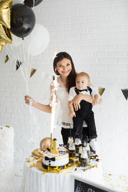 Mãe e filho comemorando o 1º aniversário juntos rindo e sorrindo com balões