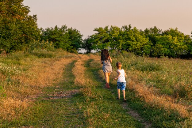 Mãe e filho correndo por uma estrada rural na zona rural. Caminhe ao ar livre na área rural antes do pôr do sol.
