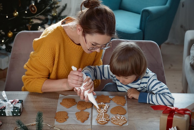 Mãe e filho decorando biscoitos de gengibre de Natal com açúcar de confeiteiro juntos
