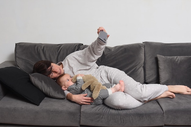 Mãe e filho deitados no sofá e fazendo uma selfie