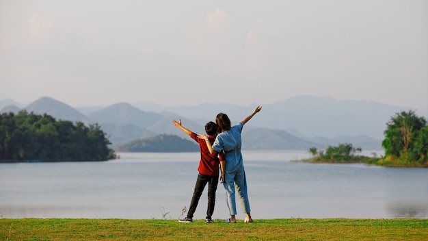 Mãe e filho em pé ao lado do grande lago e ver a vista para a montanha ao fundo. Ideia para turista em família viajar juntos para a viagem ao ar livre.