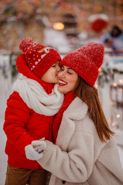 Mãe e filho em roupas quentes se divertem no inverno em uma feira de Ano Novo com neve na Praça Vermelha em Moscou