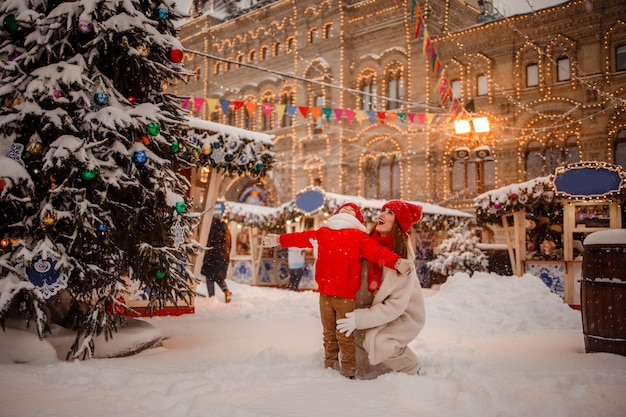 Mãe e filho em roupas quentes se divertem no inverno em uma feira de Ano Novo com neve na Praça Vermelha em Moscou