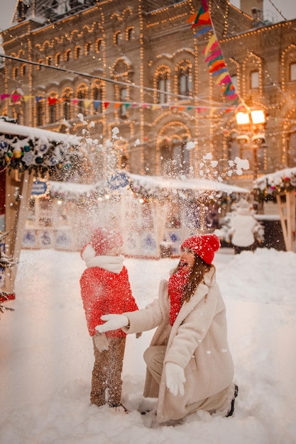 Mãe e filho em roupas quentes se divertem no inverno em uma feira de Ano Novo com neve na Praça Vermelha em Moscou