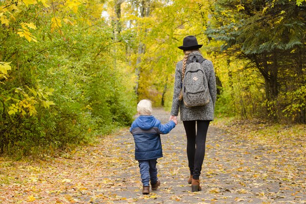 Mãe e filho estão andando na floresta de outono