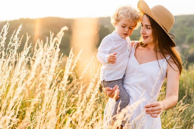 Mãe e filho estão andando na natureza ao pôr do sol