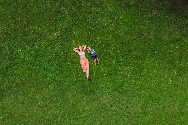 Mãe e filho estão deitados na grama do parque, fotos do drone, quadracopter.