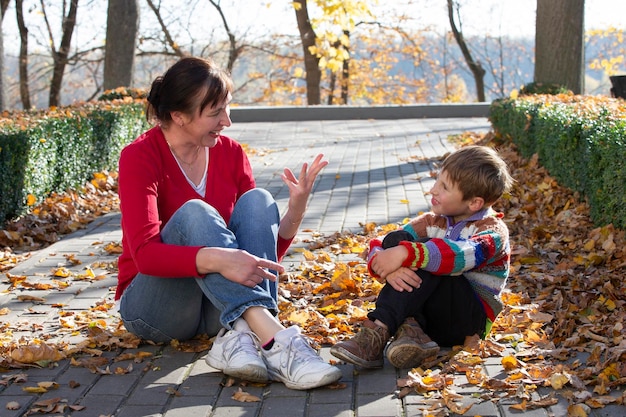 Mãe e filho estão sentados e conversando alegremente no parque outono