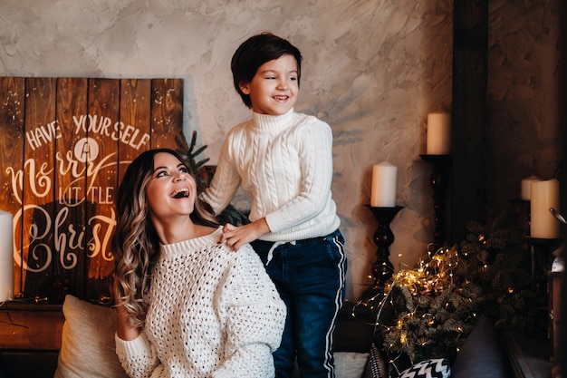 Mãe e filho estão sentados em casa no sofá antes do ano novo e sorrindo juntos.