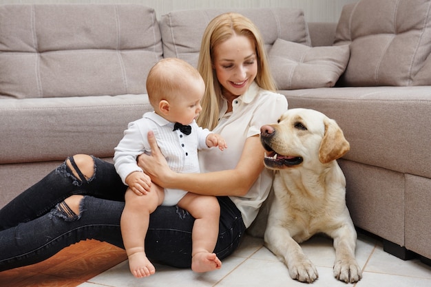 Mãe e filho estão sentados no chão com um cachorro