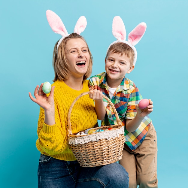 Mãe e filho felizes com ovos pintados no cesto