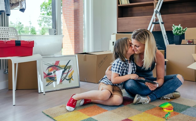 Mãe e filho jogando o tablet e beijando sentado no tapete