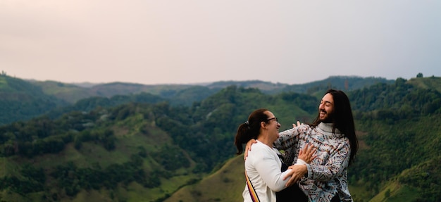 Mãe e filho latinos abraçando e rindo turistas da colômbia paisagem de montanha foto panorâmica com espaço de cópia