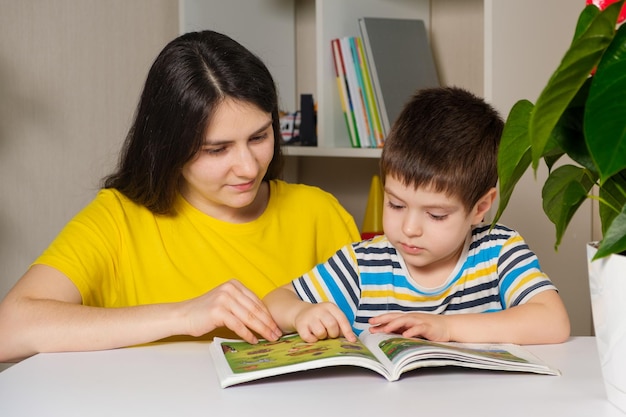 Mãe e filho lêem o livro, olham as fotos nas páginas.