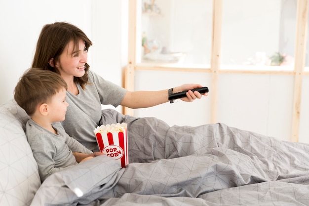 Mãe e filho na cama assistindo tv