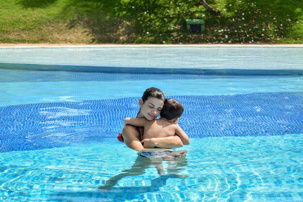 Mãe e filho na piscina se abraçando