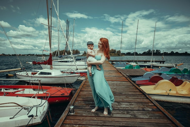 mãe e filho no cais tendo como pano de fundo barcos e iates