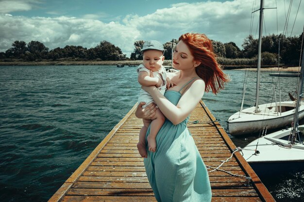 mãe e filho no cais tendo como pano de fundo barcos e iates