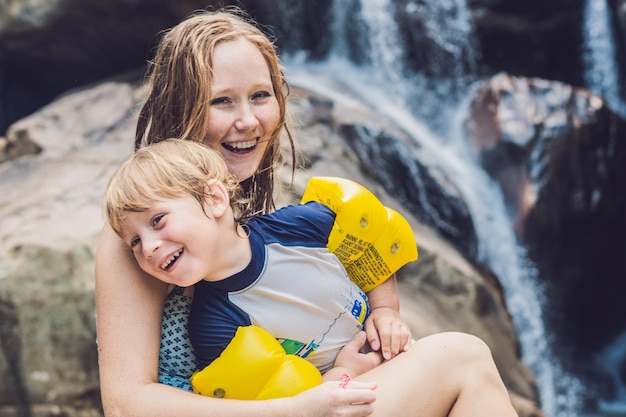 Mãe e filho no fundo da cachoeira. viajar com o conceito de crianças.