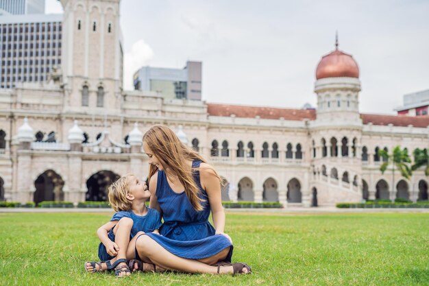 Mãe e filho no fundo da Praça Merdeka e do Edifício Sultan Abdul Samad. Conceito de viajar com crianças