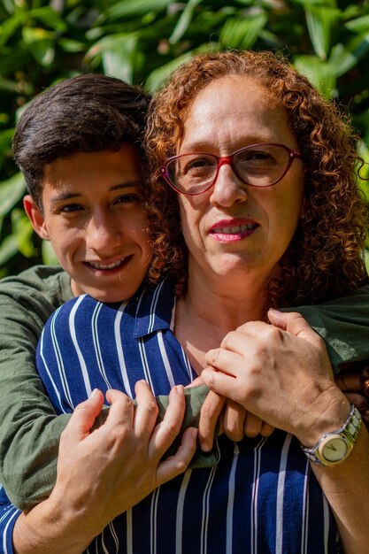 Mãe e filho olhando para a câmera na natureza em uma foto vertical de dia ensolarado