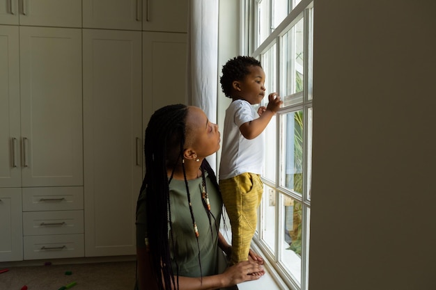 Mãe e filho olhando pela janela do quarto em casa