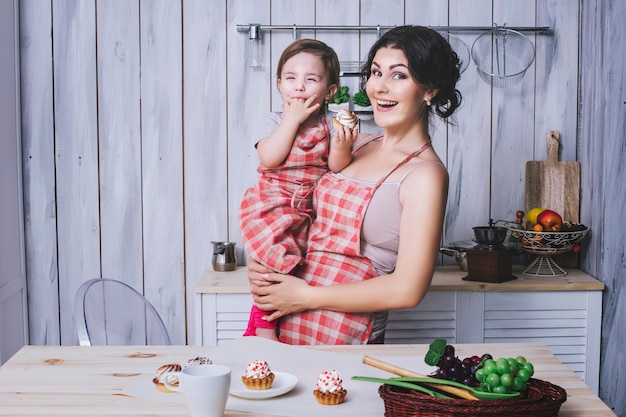 Mãe e filho pequeno na cozinha em casa com aventais