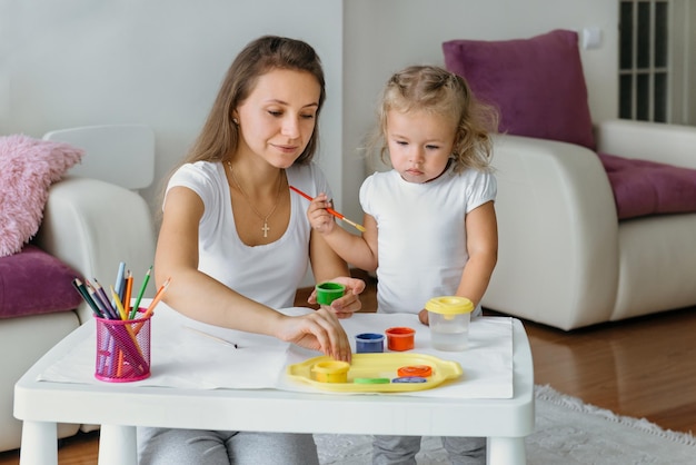 Mãe e filho pintando em casa, família criativa