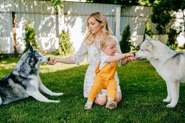 Mãe e filho posando com dois cachorros no jardim