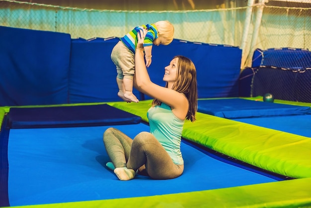 Mãe e filho pulando em uma cama elástica no parque de fitness e fazendo exercícios dentro de casa