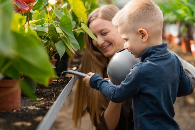 Mãe e filho regam as plantas na estufa