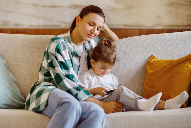 Mãe e filho relaxando com smartphone em um sofá aconchegante