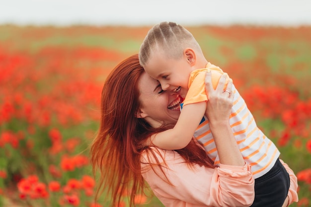 Mãe e filho rindo e se divertindo no campo de papoulas