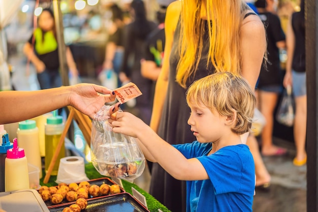 Mãe e filho são turistas no mercado de comida asiática de rua ambulante