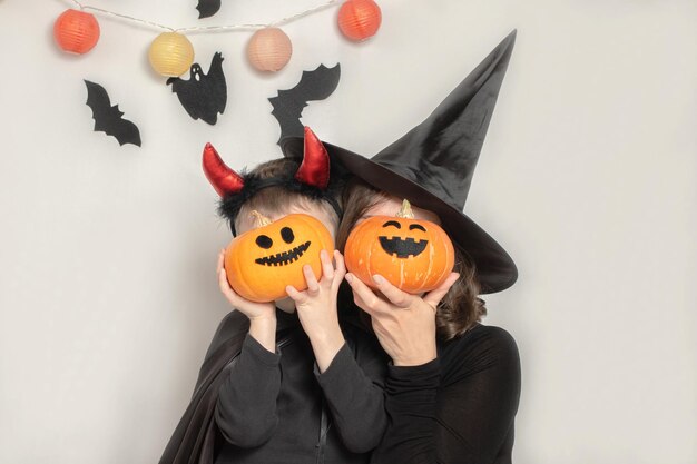 Mãe e filho se divertem celebrando o Halloween em uma fantasia de bruxa e diabo Celebração da família