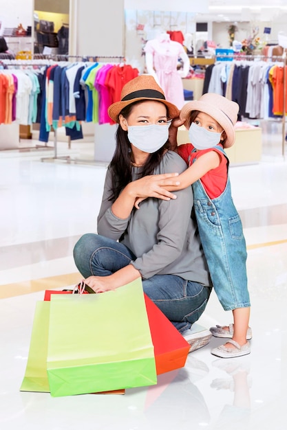 Mãe e filho seguram sacolas de compras enquanto usam máscara