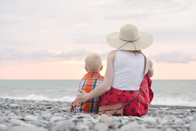 Mãe e filho sentado na praia e admirar o pôr do sol