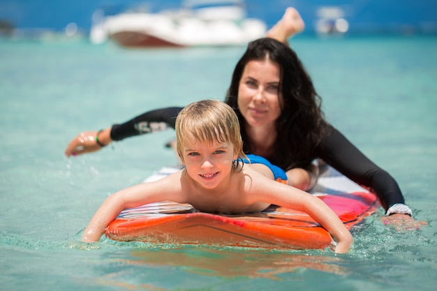 Mãe e filho surfando no oceano na lousa