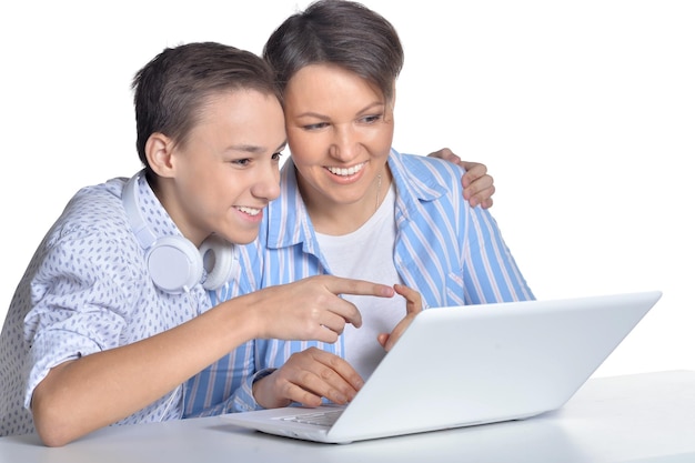 Mãe e filho usando laptop posando contra branco