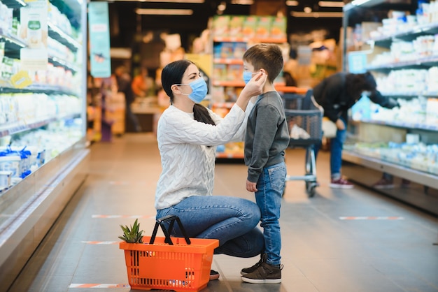 Mãe e filho usando máscara protetora loja em um supermercado durante a epidemia de coronavírus