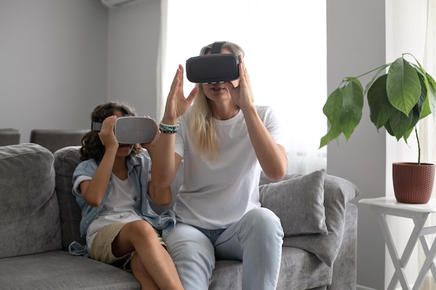 Mãe e filho usando óculos de realidade virtual fone de ouvido vr na sala de estar em casa se divertindo