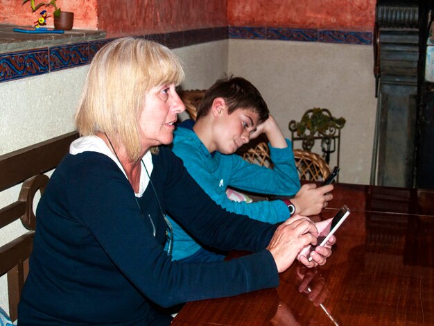 Foto mãe e filho usando smartphone enquanto estão sentados na mesa em casa