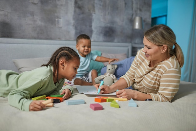 Mãe e filhos brincando na cama