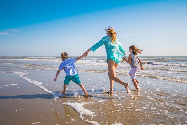 Mãe e filhos brincando no mar na praia