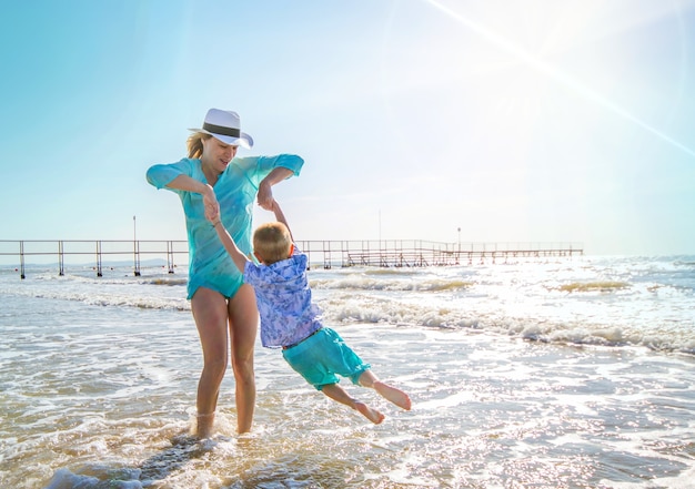 Mãe e filhos brincando no mar na praia