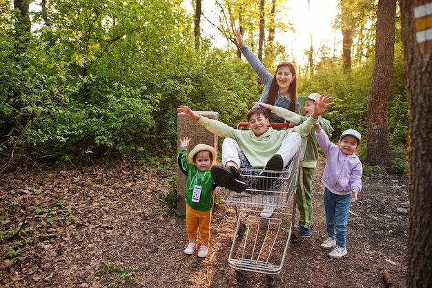 Mãe e filhos com carrinho se divertindo na floresta