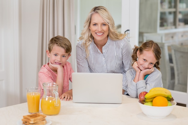 Mãe e filhos com laptop na cozinha