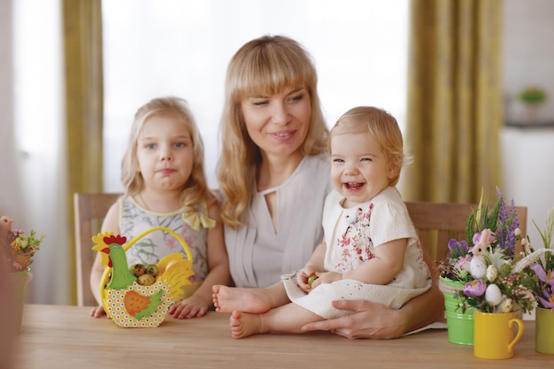 Mãe e filhos com ovos de páscoa coloridos na mesa de jantar