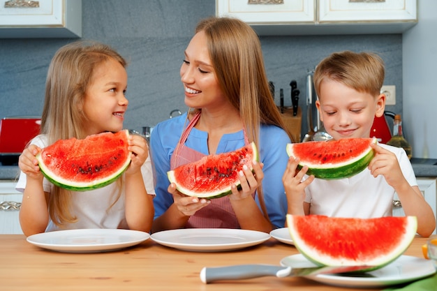 Mãe e filhos comendo melancia