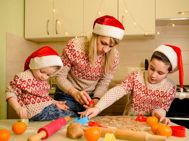 Mãe e filhos cozinhando biscoitos de natal em casa sobremesas saborosas